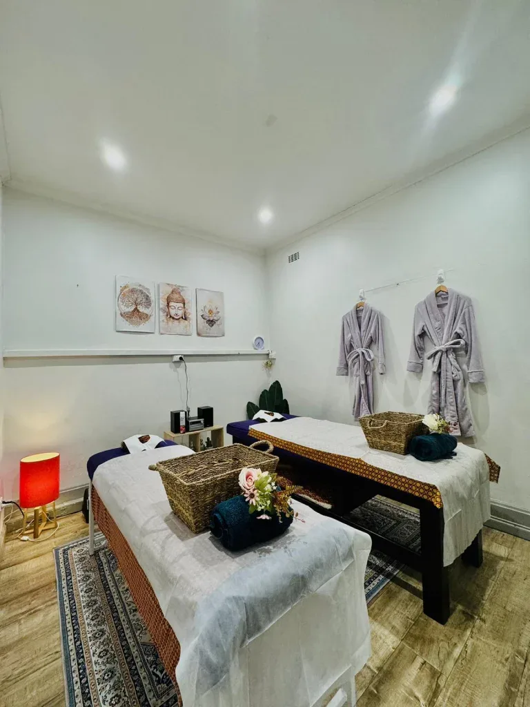 The real couples room — twin tables, grey robes, Buddha wall art, warm red lamp